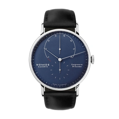 Nomos Lambda mit tiefblauem Zifferblatt, weissen Indizes mit Superluminova. Kleine Sekunde bei 6 Uhr. Geh&auml;use aus 18 Karat Weissgold mit schwarzen Horween Genuine Shell Cordovan Lederband. Die Gangreserveanzeige mit 84 Stunden in Bogenform.